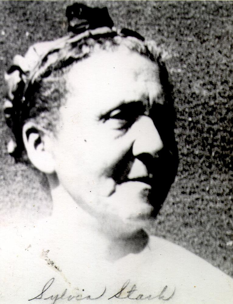 black and white portrait of middle-aged woman hair pulled back with a decorative band.