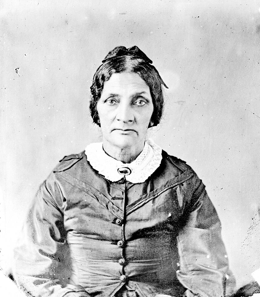 black and white professional portrait, facing the camera, hair pulled back, wearing muted colored dress with white collar held by a brooch