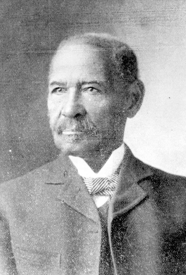 Portrait. Black male age 50, dressed semi-formally wearing jacket, vest, winged-collar white shirt with a striped pattern bow-tie.
