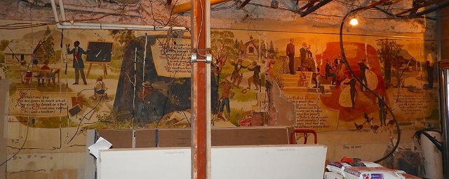 image of cracking walls of a wall mural; renovation and construction materials can be seen in the foreground