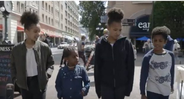 4 youth, ranging in age from 6 to 15, walking side by side in historic square