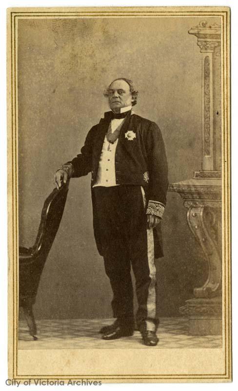 official professional portrait of older man standing, tuxedo, winged collar, medal on lapel