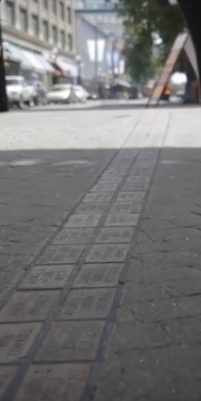 public square showing pavement with double row of gray bricks with etched names