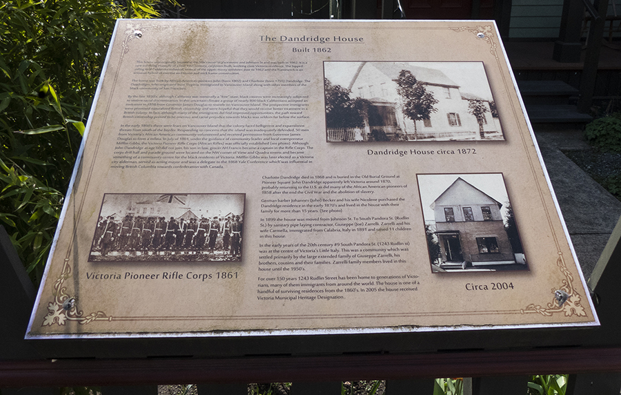 commemorative plaque with text and 3 images mounted on a fence at a slight angle visible to passersby