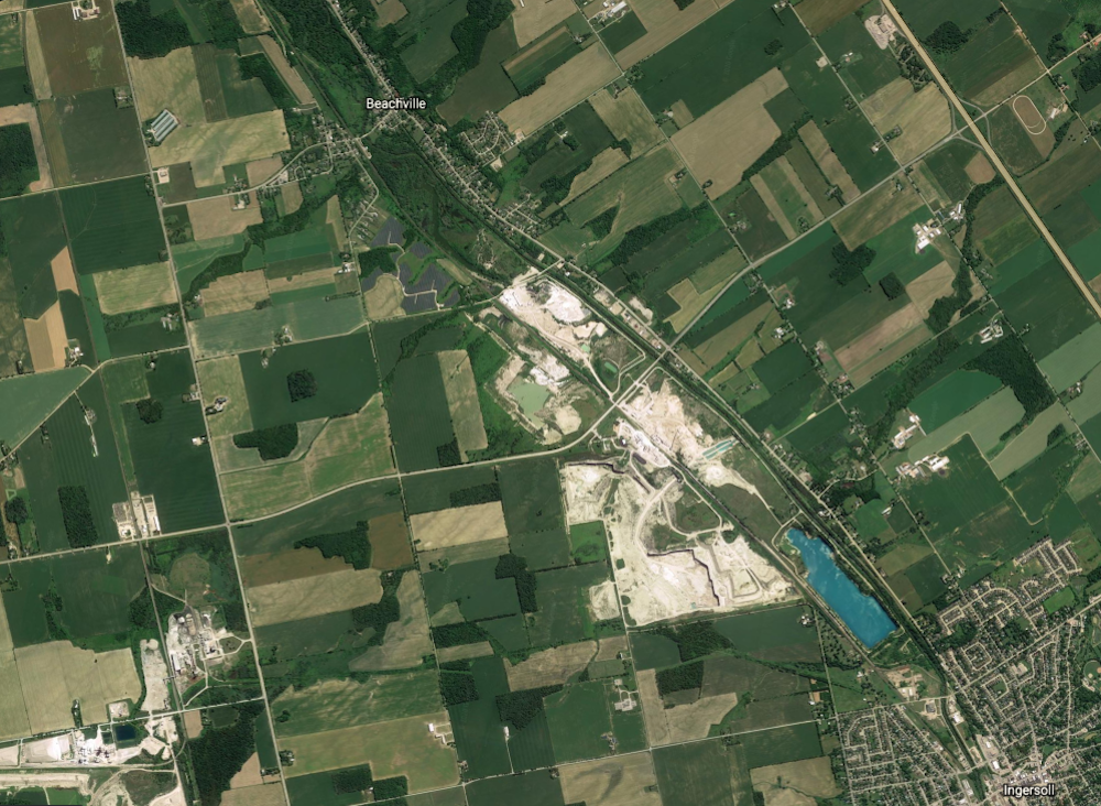 A satellite image of roads, quarry pits and farmlands between a village and a town
