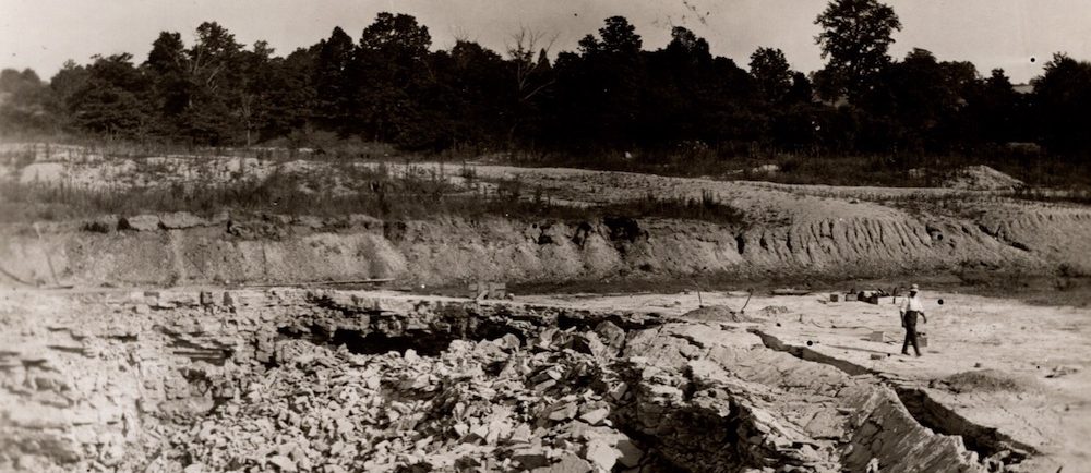 A man walks beside layers of shattered rock