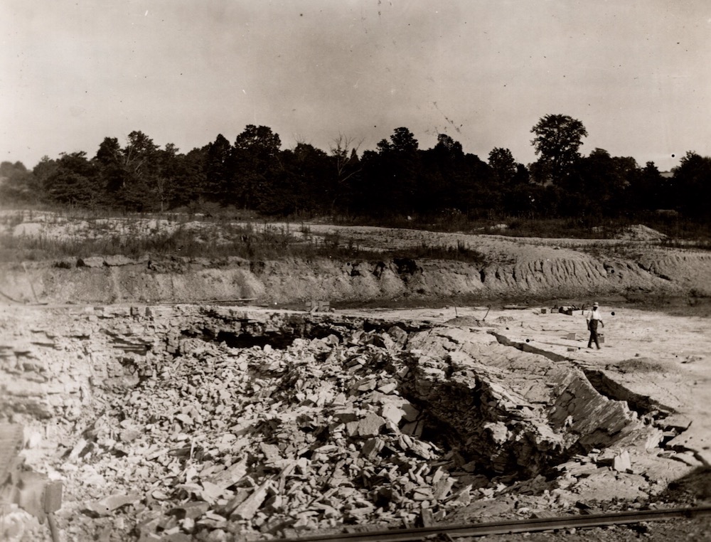 A man walks beside layers of shattered rock