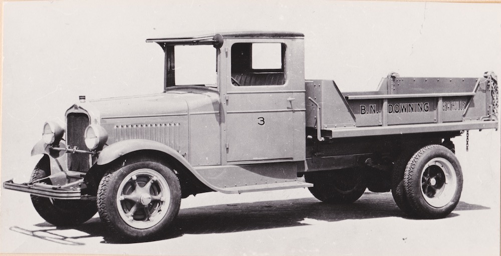 A black and white image of an early pick up truck with a number 3 on its door and the company name, B.N. Downing, on its bed