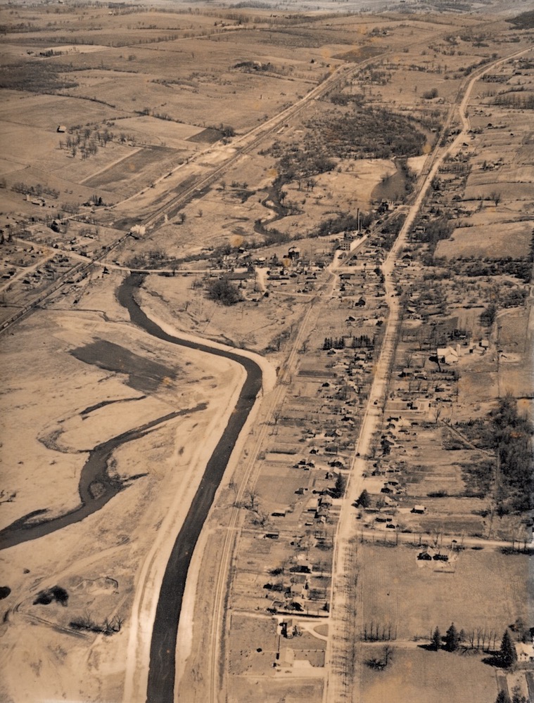 An aerial photograph of a river and a road that run parallel to another