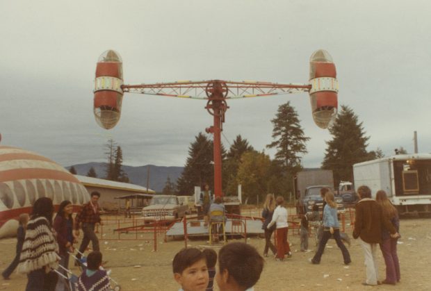 A Loop-O-Plane ride at a carnival midway, a spinning ride with one large passenger bucket each side, set up like a pendulum