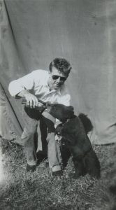 Une photo en noir et blanc du jeune Bingo Hauser en train de nourrir un ourson noir au biberon