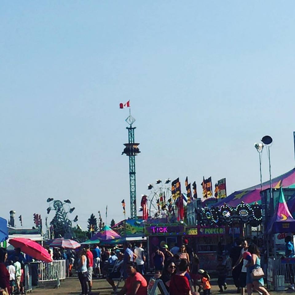 A carnival midway with many rides and concessions set up, seen in the distance are the Zipper, Super Shot and Ferris wheel rides, a carousel can be seen in front