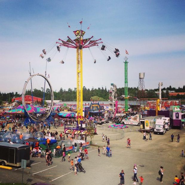 A large view of a carnival midway set up in a parking lot, the Vertigo ride is featured in the middle