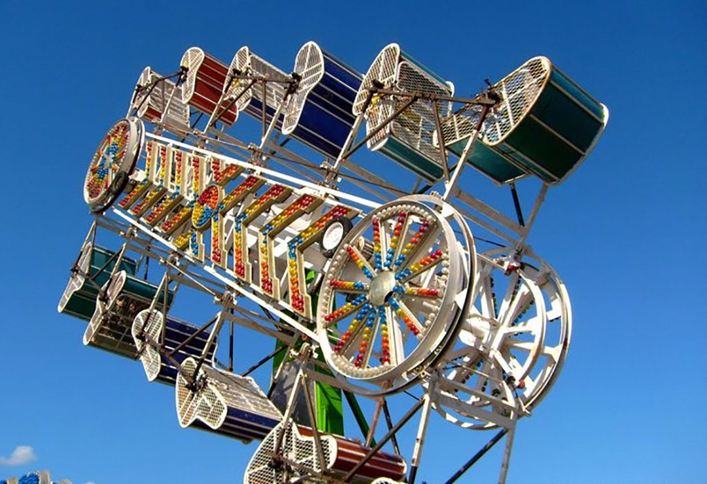 Zipper carnival ride, has different coloured ride buckets on both vertical sides, the buckets spin around as the ride moves