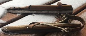 Close up of old vintage speed skates, no actual shoe attached, just rope and leather straps attached to wood with a blade at the bottom