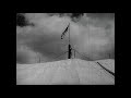 Thumbnail of black and white image of the very top of a circus tent, mostly canvas and a little flag in the middle