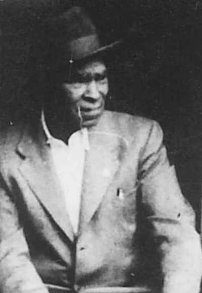 Black and white archival portrait photograph of a Black man wearing a suit and hat.
