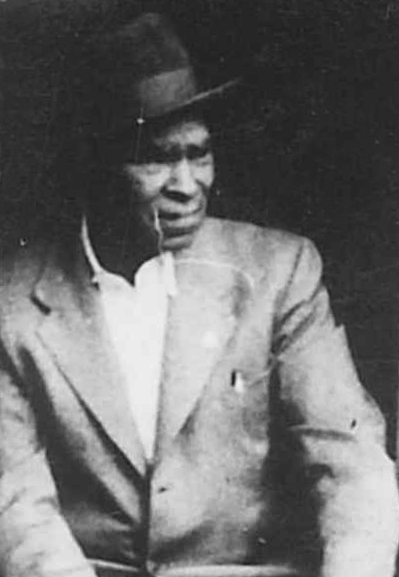 Black and white archival portrait photograph of a Black man wearing a suit and hat.