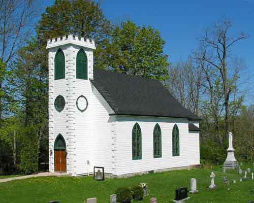 Colour photograph showing the exterior of St Peter's Anglican Church with the graveyard to right in.