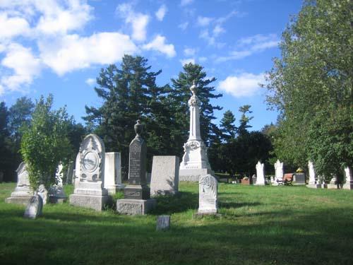Colour photograph of graves in Alexander Gibson Memorial Cemetery with green grass and headstones.