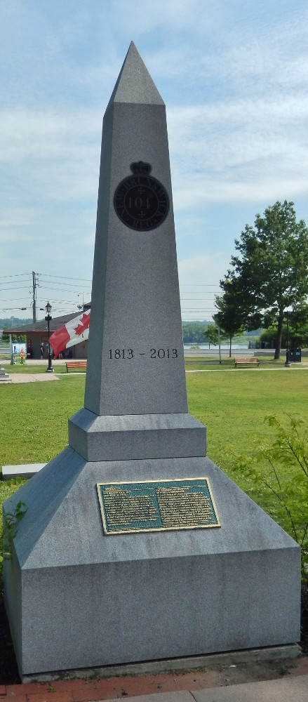 Colour photograph of the 104th foot regiment monument at the entrance to Officer's Square in Fredericton. In the background can be seen green grass and park buildings.