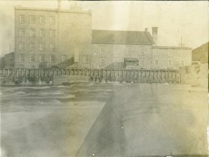 Une rivière coule par-dessus un barrage, devant un bâtiment de cinq étages. 