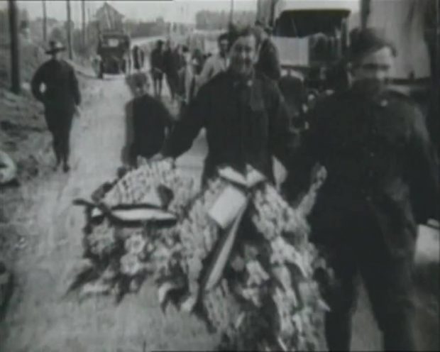 Two men in military uniforms carrying wreaths.