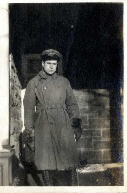 Man standing on a veranda wearing a military uniform.
