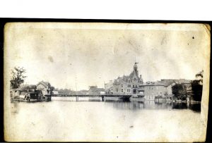 A river with a flat bridge spanning it and buildings on both banks.