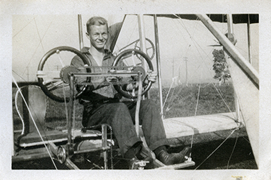 A man sitting in the pilot’s seat of a bi-plane.