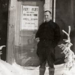 A man standing in the snow in front of a door.