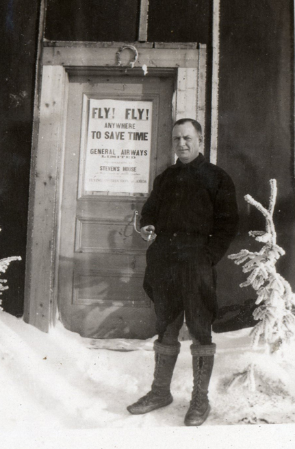A man standing in the snow in front of a door.
