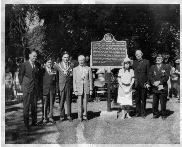 A group of people standing in front of a large, raised plaque.