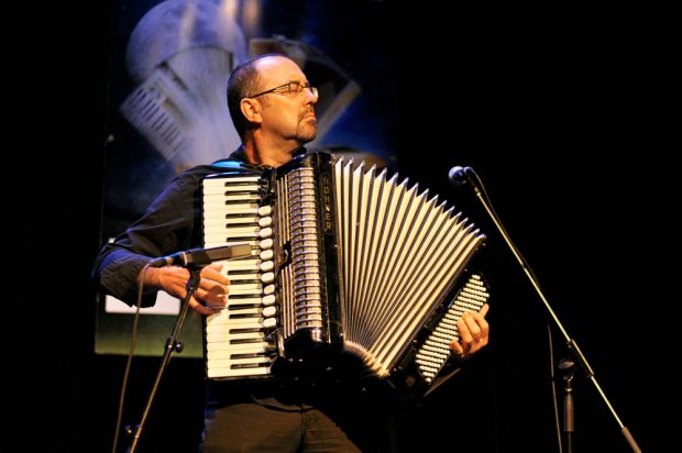 Colour photograph of Martin Bellemare standing and playing piano accordion, as he faces the audience with his eyes closed.