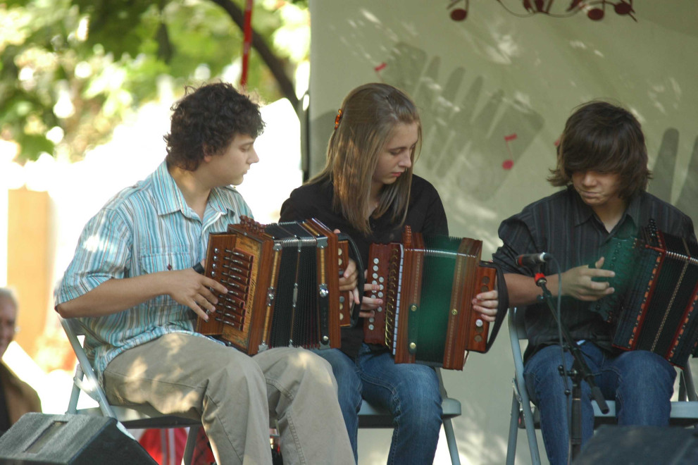 Color photography, three young accordionists sitting on chairs and very concentrated, play for the first time in front of public.