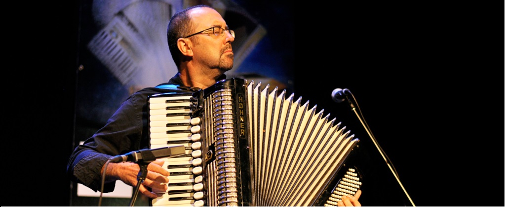 Colour photograph of Martin Bellemare standing and playing piano accordion, as he faces the audience with his eyes closed.