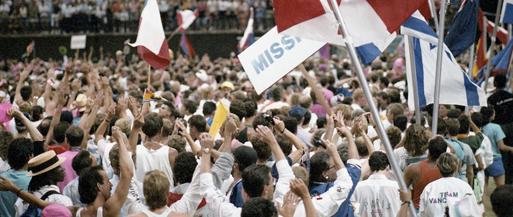 Crowds of athletes and other participants, waving various national flags at the Celebration '90 Opening Ceremony.