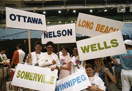 A group of Canadian female athletes hold signs with the names of their hometowns on the floor at B.C. Place Stadium during Closing Ceremonies.