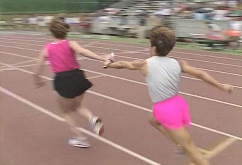 Two women pass the baton in women's relay race at Swanguard Stadium, Burnaby.