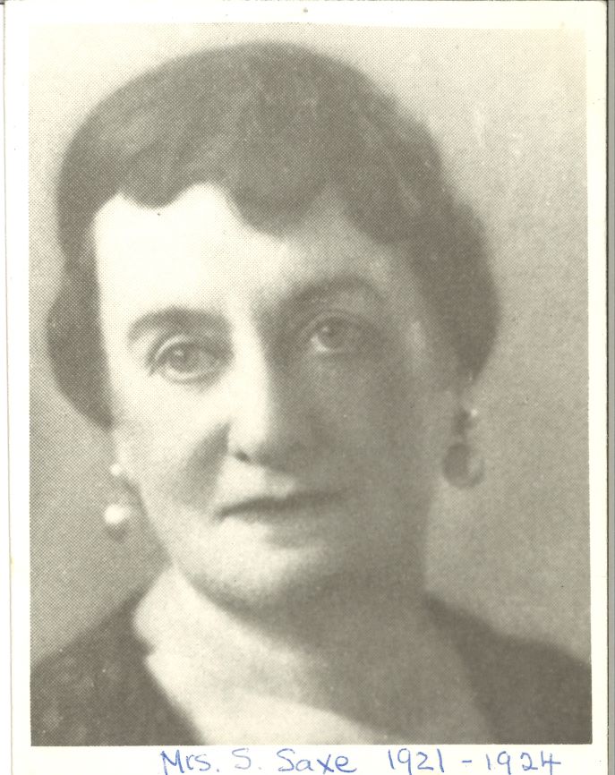 A black-and-white photograph of a middle-aged woman with pulled back hair and earrings.