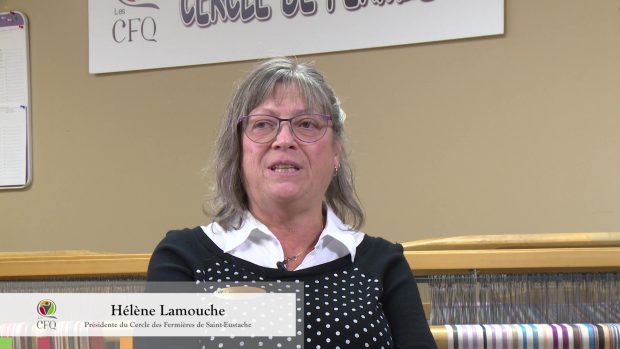 Close-up of a woman with grey hair speaking. She wears a black shiirt with white dots and is sitting in front of a loom. In the left lower corner, we can read that she is Hélène Lamouche, president of the Cercle de Fermières Saint-Eustache.