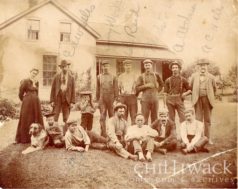 Portrait de groupe des travailleurs et des familles de la ferme Edenbank sur deux rangées devant une maison 