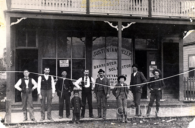 Group portrait of men and boys standing in front of the Justinian Pelly Law Office