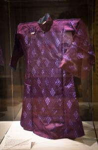 Vue de trois-quarts d’une veste de soie pourpre dans une vitrine d’exposition 