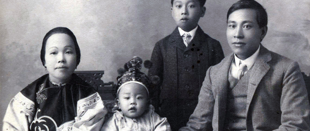 Formal black and white portrait of who is assumed to be the Yip On family. The youngest is in the centre wearing a crown with the mother on left and father on right. Their young boy is standing off centre behind the seated family.