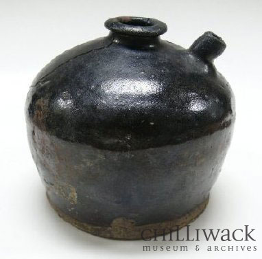 Hand-made black earthenware pot with a top opening and short spout.