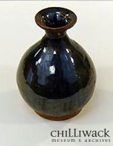 Dark brown glazed tiger whiskey bottle with fluted neck.