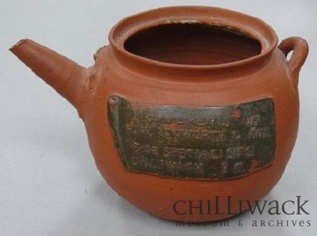 Terracotta-coloured earthenware teapot with embossed lettering on the side.