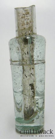 Blue-tinted, four-sided glass Chinese medicine bottle. The bottle is cracked at the top.