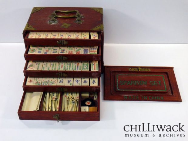 Mahjong game set housed in a wooden box with five drawers opened to expose the tiles and supplies.